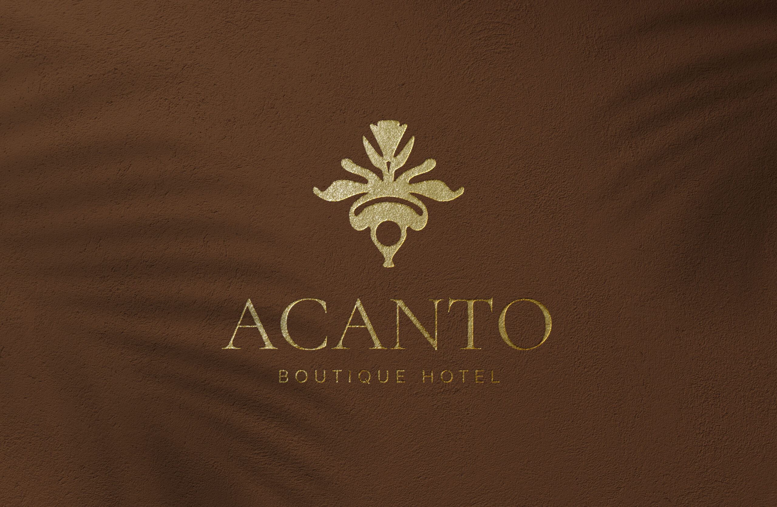 Logotipo de ACANTO Boutique Hotel estampado en dorado sobre un muro de estuco color terracota